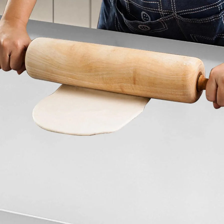 Person using a wooden rolling pin to flatten dough on a gray surface
