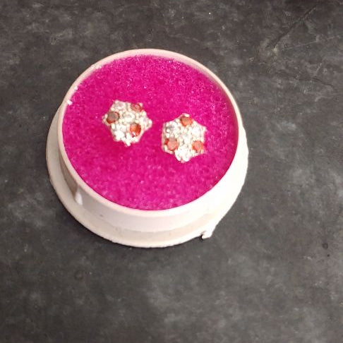 Pair of earrings in a pink jewelry box on a dark surface with flowers in the background