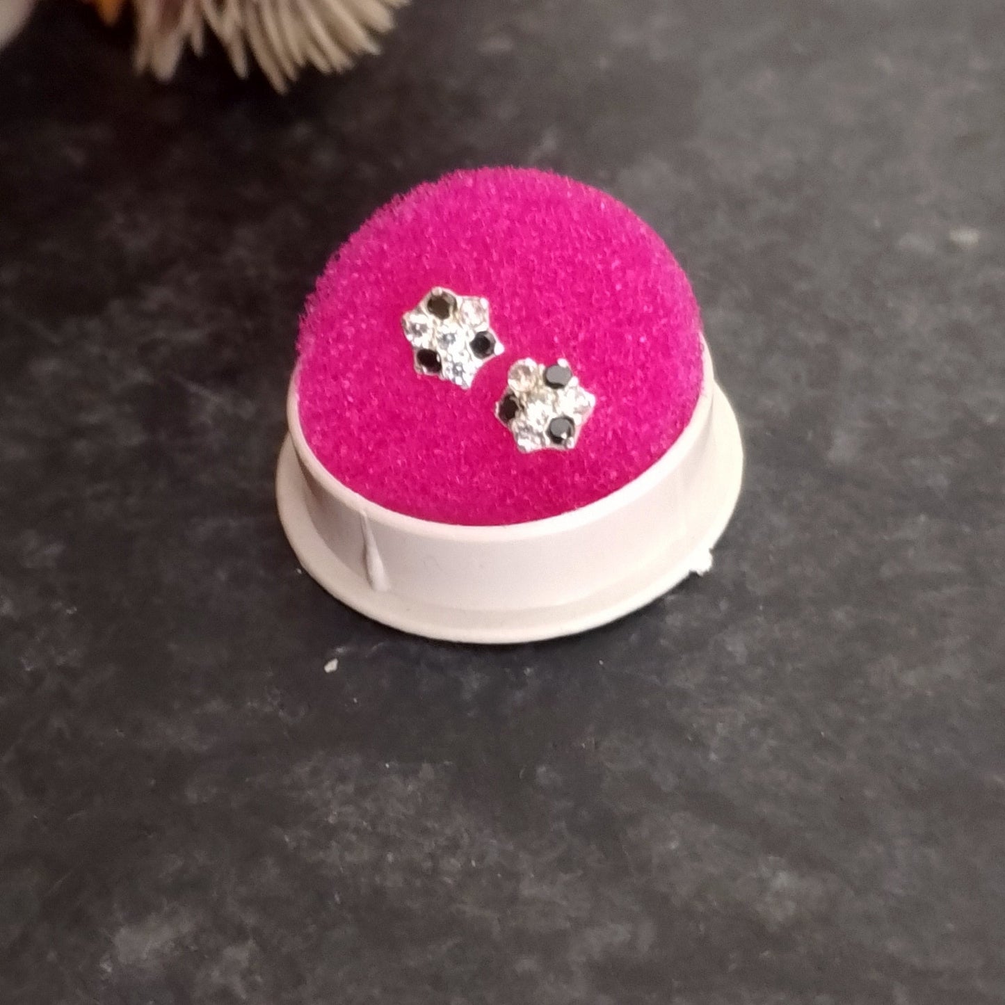 Pink jewelry display with earrings on a dark surface