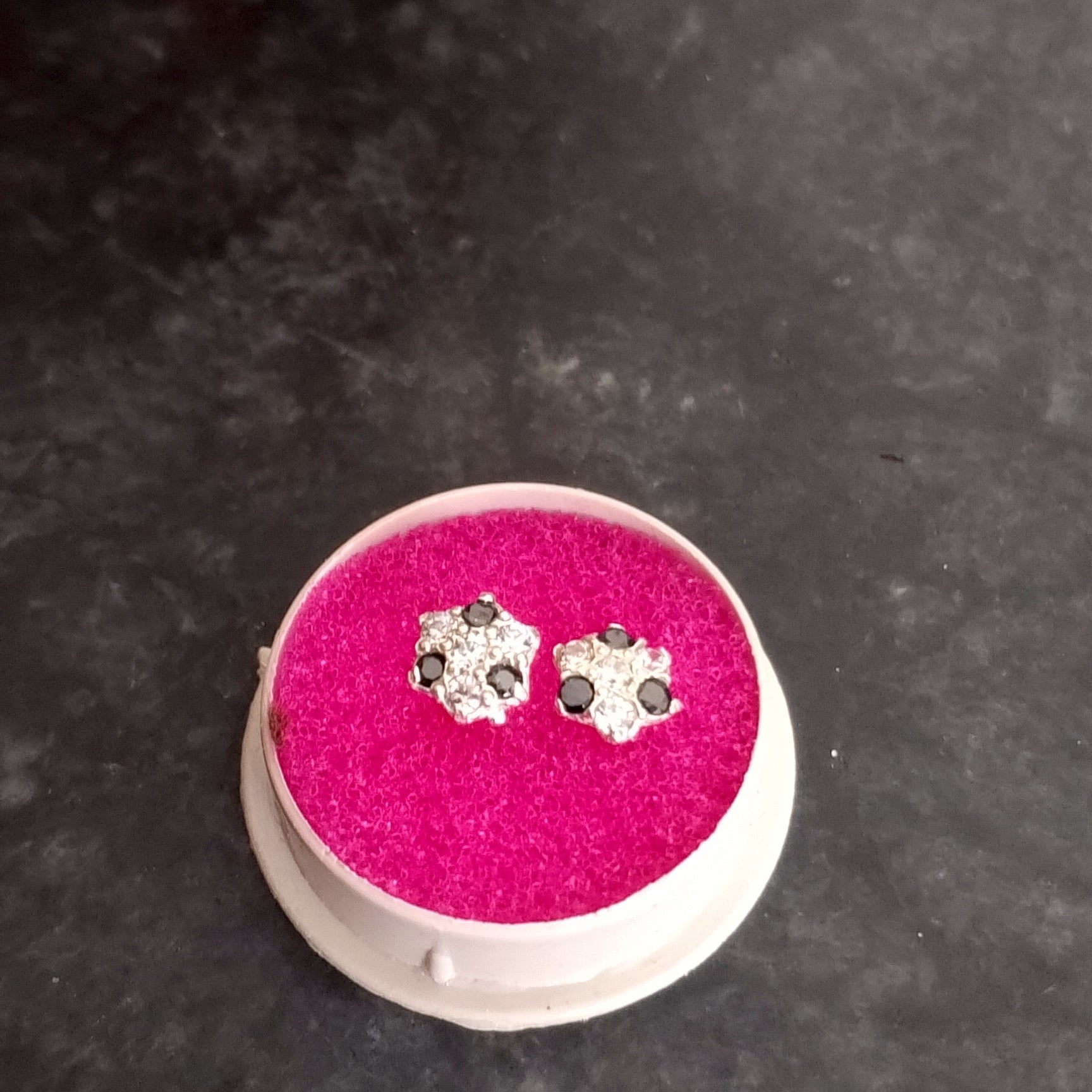 Silver earrings on pink心动垫子 against a dark background