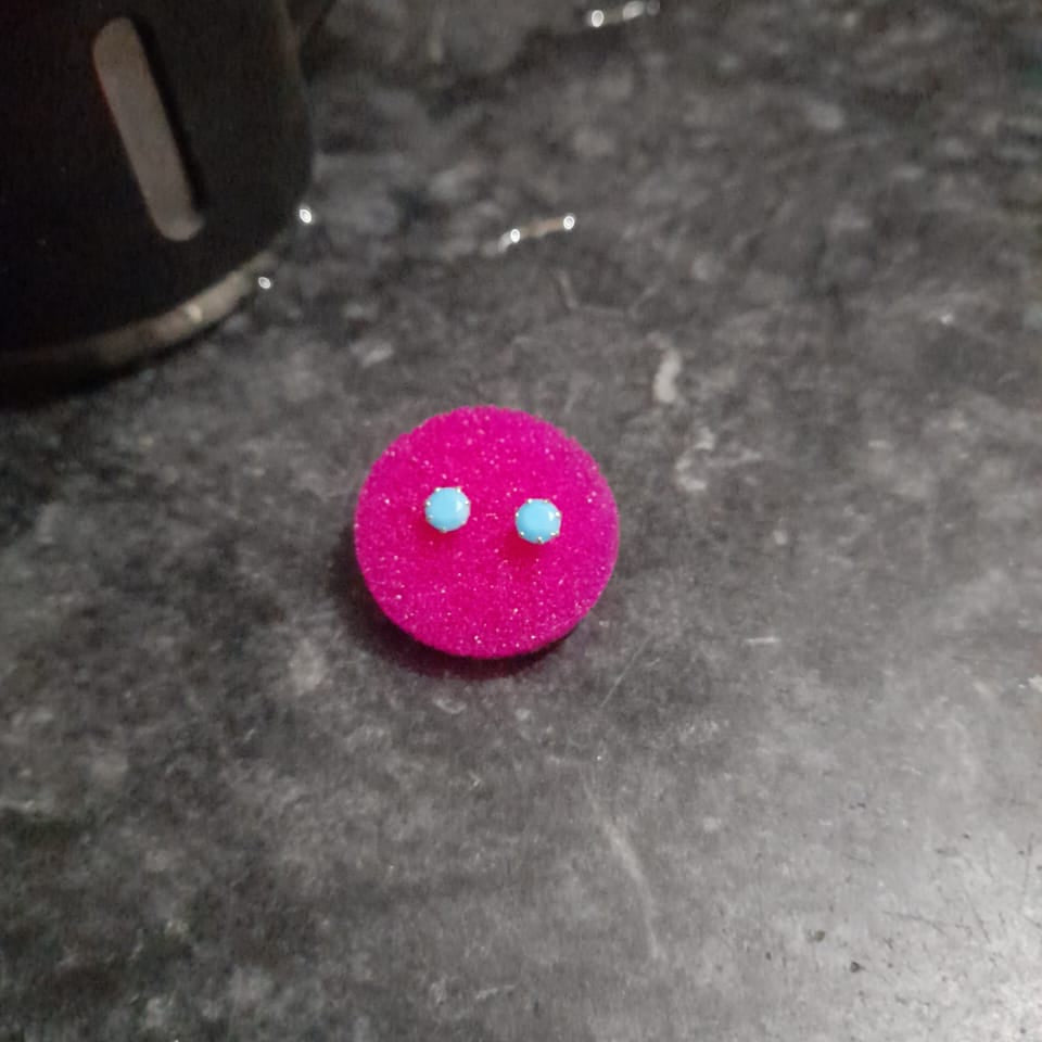 Pink earrings with blue stones on a dark surface